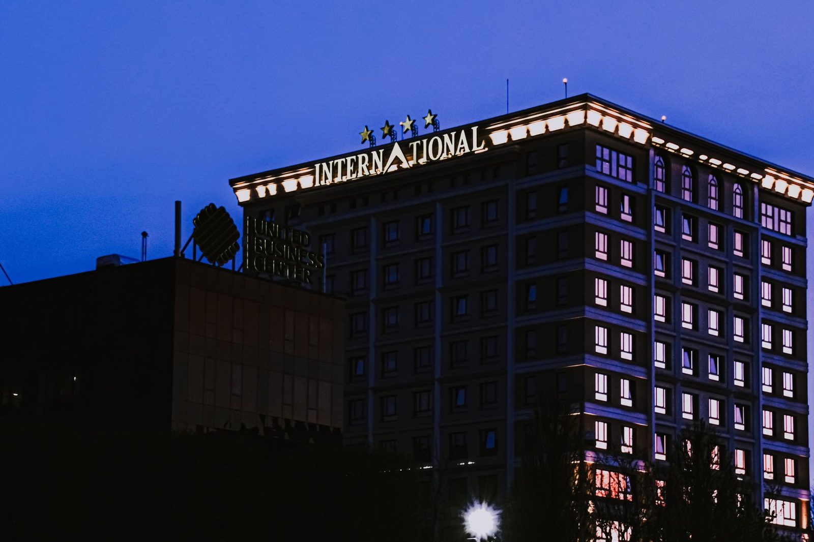 Multistory modern hotel with glowing carnice and light in windows located in city on street in night time