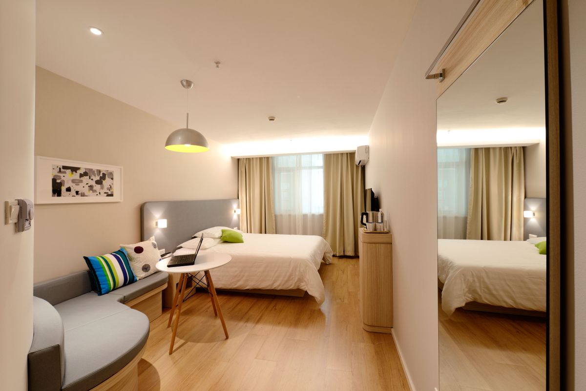 Hotel bedroom with a bed, sofa, small table and mirrored wardrobe