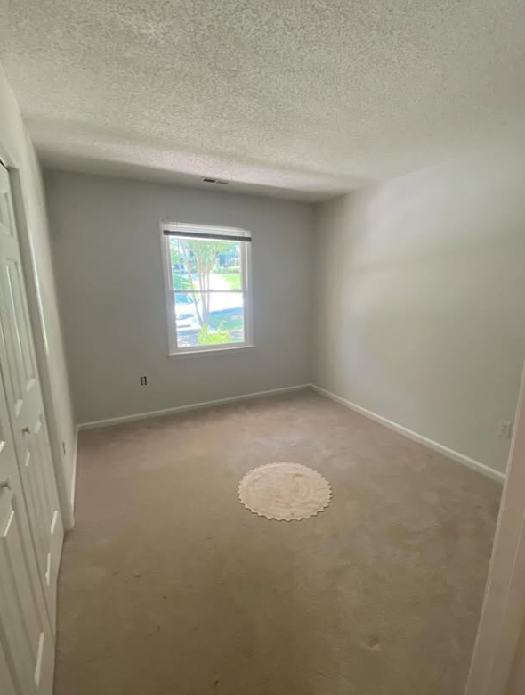 A bedroom with old carpet before the hardwood was uncovered