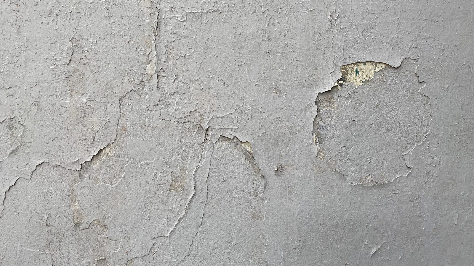 Detailed texture of a weathered wall with peeling paint and cracks, perfect for backgrounds.