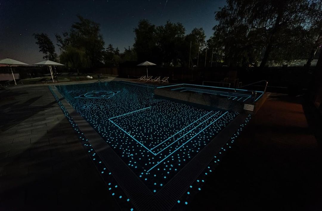Completed swimming pool finished with blue mosaic tiles at night